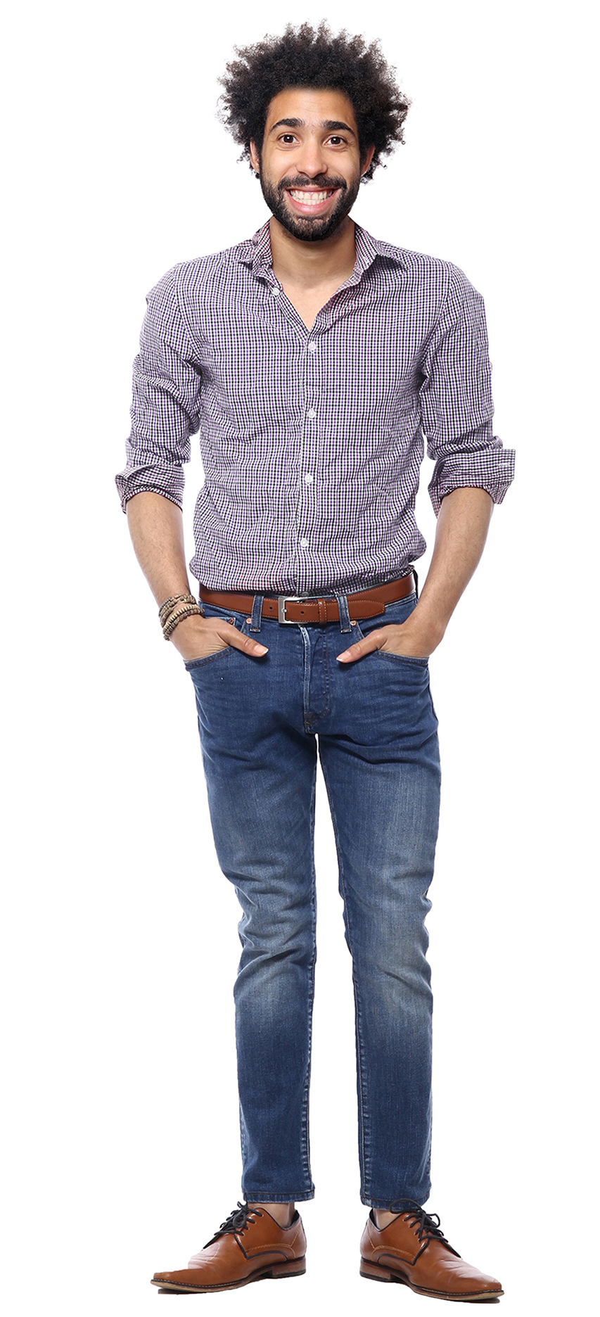 A man wearing a button-down, jeans, and oxfords stands confidently with his hands in his pockets.