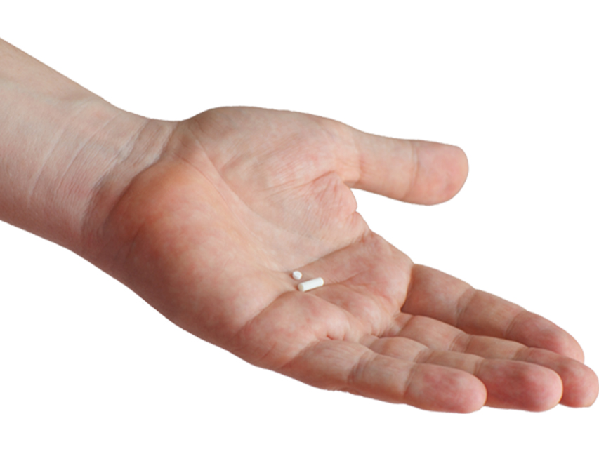 A hand with the palm up holds two pills.